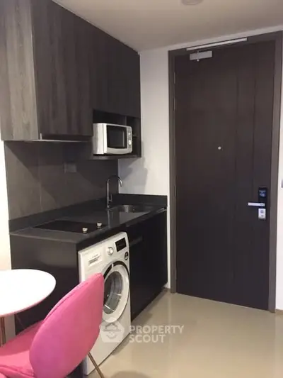 Modern compact kitchen with washing machine and microwave in sleek apartment