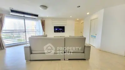 Spacious living room with modern sofa and city view balcony.