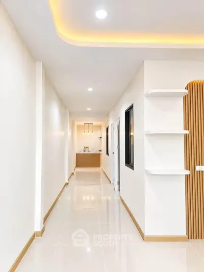 Sleek modern hallway with recessed lighting leading to a stylish kitchen area.