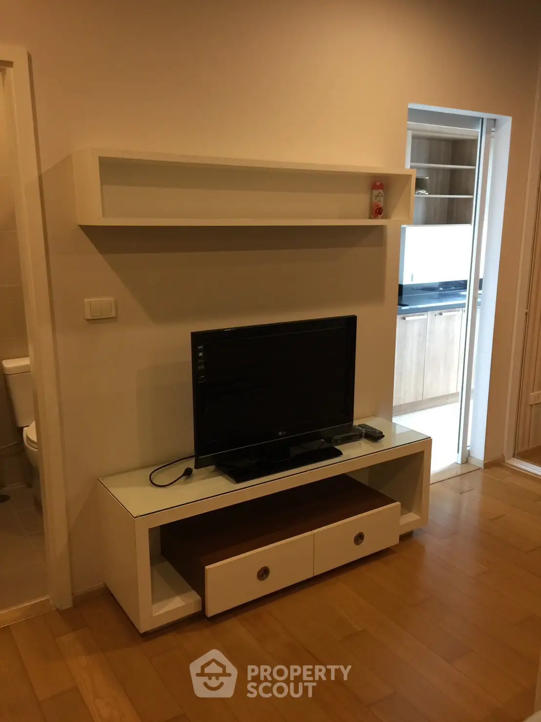 Modern living room with sleek TV stand and open kitchen view, perfect for contemporary living.