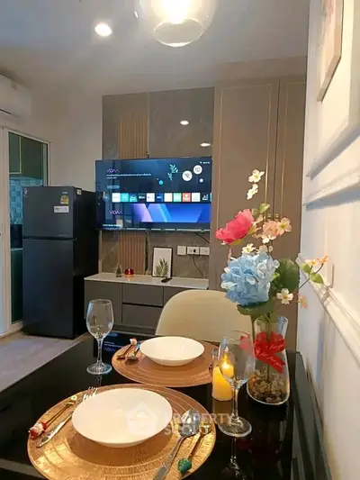 Modern dining area with elegant table setting and wall-mounted TV in stylish apartment.