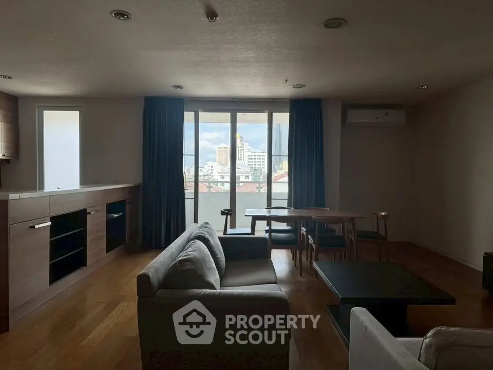 Spacious living room with modern furniture and large windows offering city views.