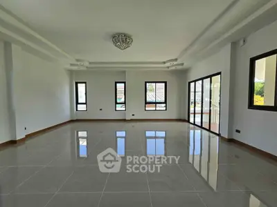 Spacious modern living room with large windows and glossy tiled floors, perfect for natural light and open living.