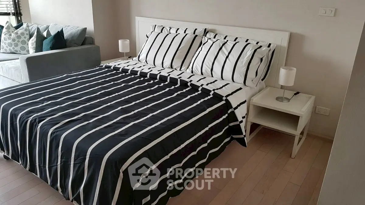 Modern bedroom with stylish striped bedding and cozy seating area