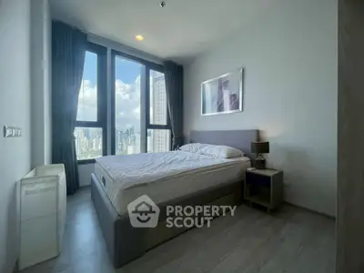 Modern bedroom with large windows offering stunning city views in a high-rise apartment.
