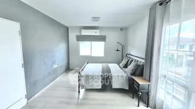 Spacious modern bedroom with minimalist decor and large window for natural light.