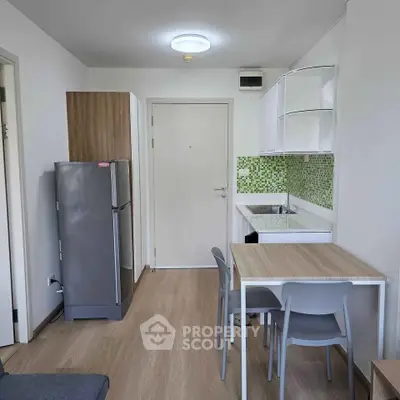 Modern compact kitchen with dining area and sleek appliances in a cozy apartment.