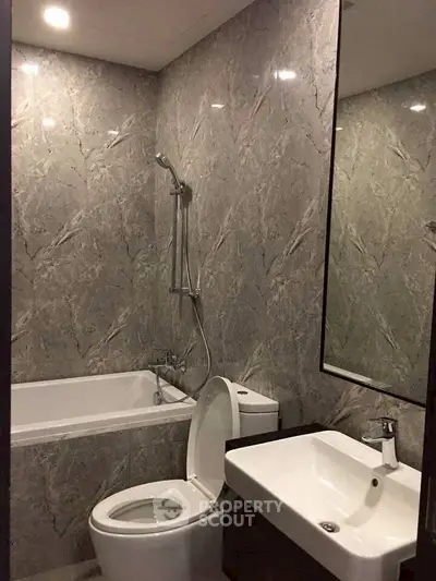 Modern bathroom with marble walls, bathtub, and sleek fixtures.