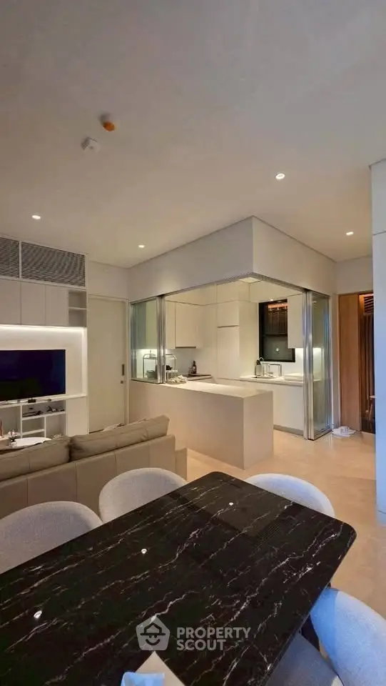 Modern open-plan living room and kitchen with sleek design and marble dining table.