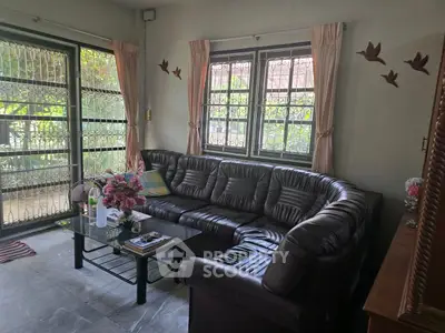 Cozy living room with leather sofa and garden view, perfect for relaxation.