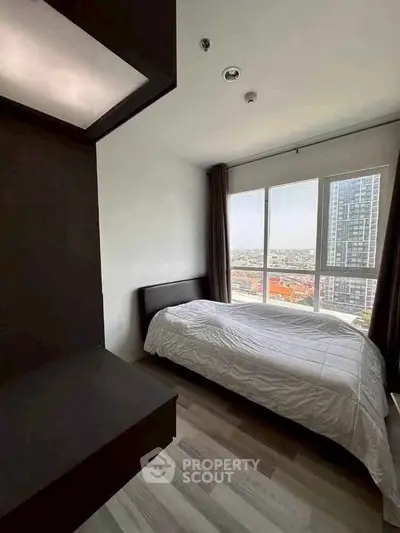 Modern bedroom with large window offering stunning city views in high-rise apartment.