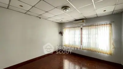 Spacious empty room with large window and wooden flooring