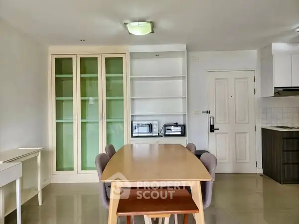 Spacious dining area with modern table and chairs, built-in shelves, and adjacent kitchen.