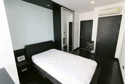 Modern minimalist bedroom with sleek black and white decor and mirrored closet doors.