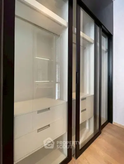 Spacious walk-in closet with sleek sliding glass doors and modern storage solutions.