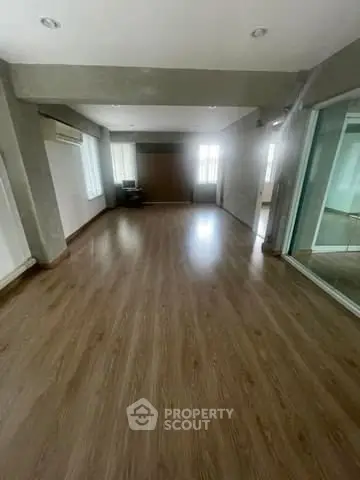Spacious empty room with wooden flooring and large windows, ideal for customization.