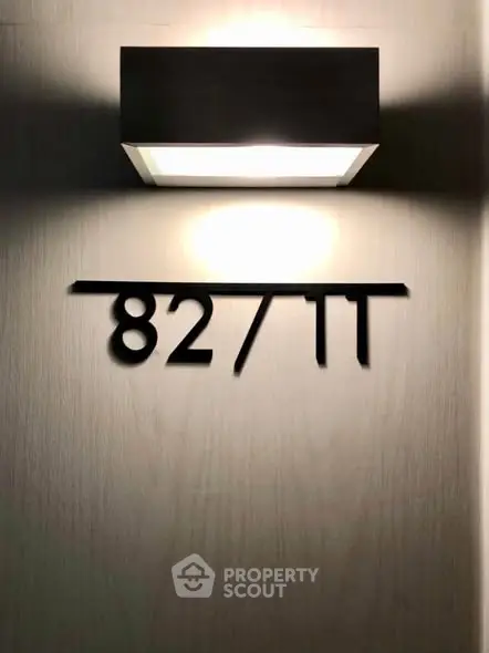 Modern apartment number sign with sleek wall light fixture.