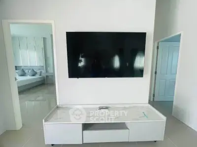 Modern living room with wall-mounted TV and sleek marble-top console, adjacent to a stylish bedroom.