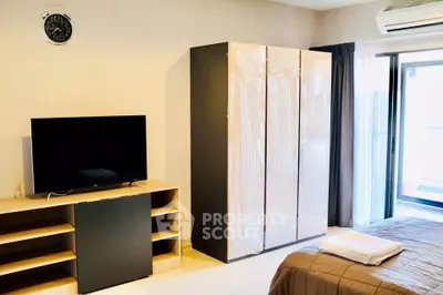 Modern bedroom with TV, wardrobe, and balcony access in a stylish apartment.