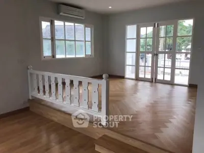 Spacious living room with elegant wooden flooring and large windows for natural light.