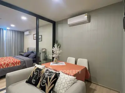 Modern apartment interior with cozy living room and stylish bedroom separated by glass partition.