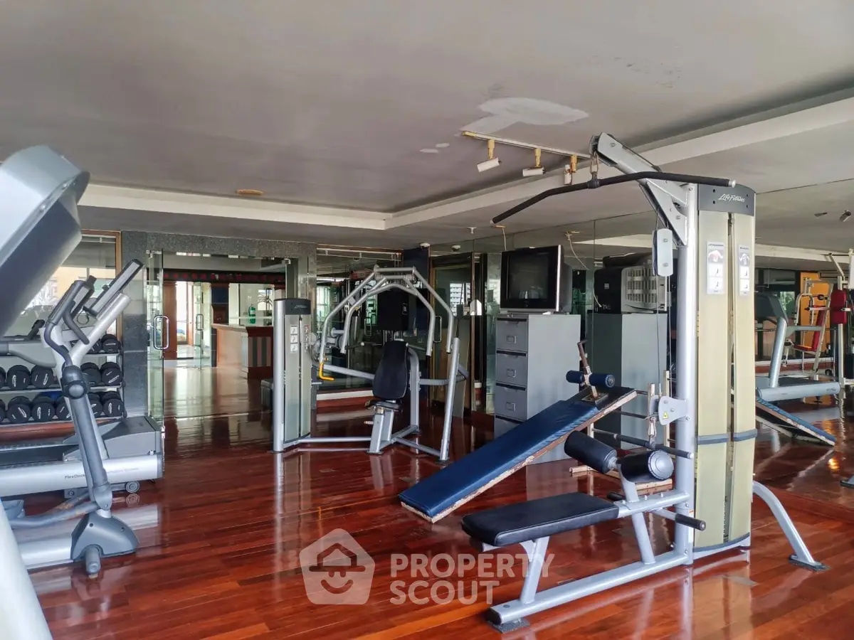 Spacious gym with modern equipment and wooden flooring in luxury real estate property.