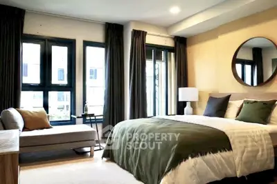 Luxurious bedroom with large windows and elegant decor, featuring a cozy bed and stylish chaise lounge.