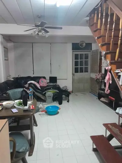 Cozy living room with staircase and ceiling fan, ideal for family gatherings.