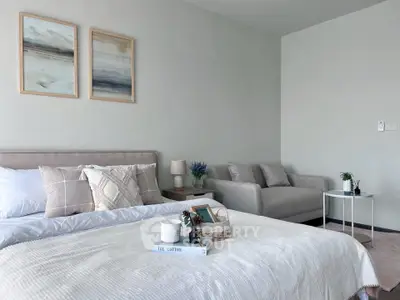Modern bedroom with cozy decor, featuring a stylish bed, elegant artwork, and a comfortable seating area.