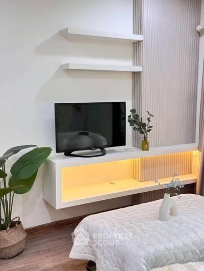 Modern bedroom with sleek TV setup and stylish decor, featuring elegant lighting and contemporary design.