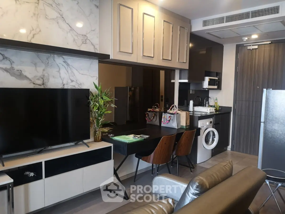 Modern open-layout living room with kitchen, featuring marble accents and sleek appliances.