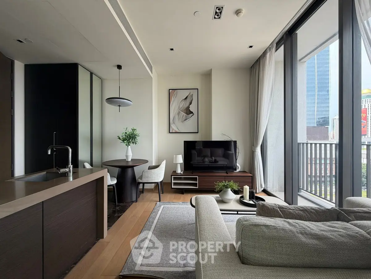 Modern living room with open kitchen and city view balcony, featuring sleek furniture and elegant decor.