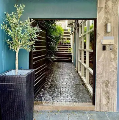 Charming entrance with lush greenery and modern design elements.