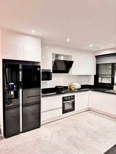 Modern kitchen with sleek black and white design, featuring built-in appliances and ample counter space.