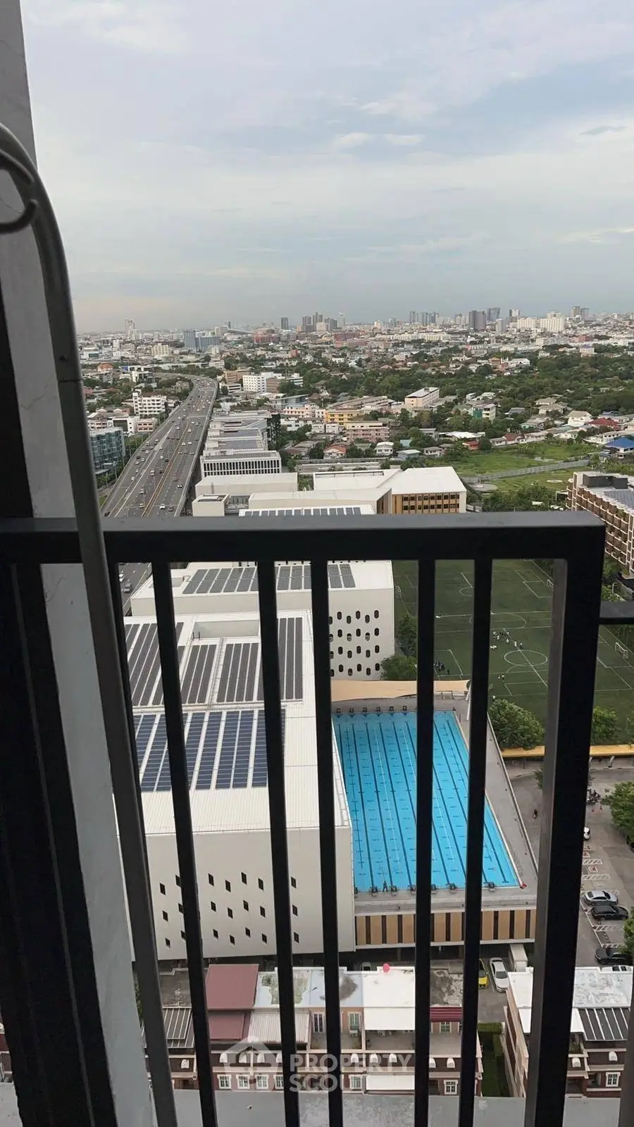 Stunning cityscape view from a high-rise balcony overlooking urban landscape and pool.