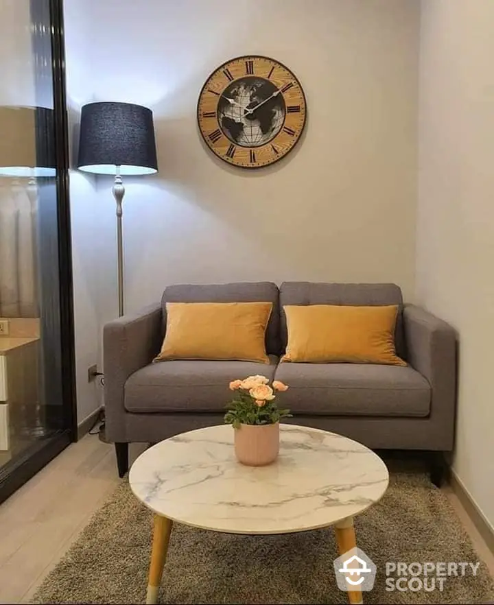 Cozy modern living room with stylish grey sofa, chic marble coffee table, and an eye-catching large wall clock, perfect for urban living.