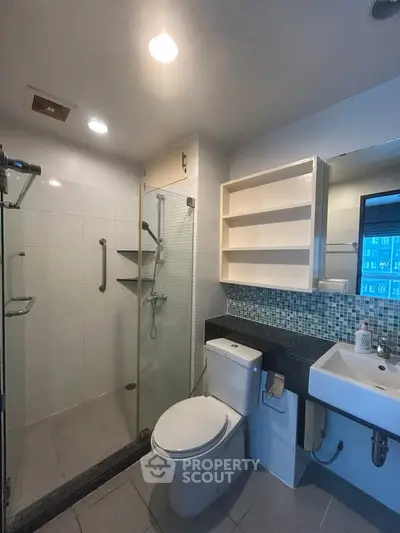 Modern bathroom with glass shower and sleek fixtures in a contemporary apartment.