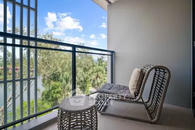 Charming balcony with stylish seating and scenic view of lush greenery and blue sky.