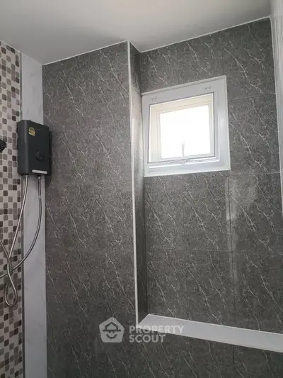 Modern bathroom with stylish grey tiles and a compact window for natural light.