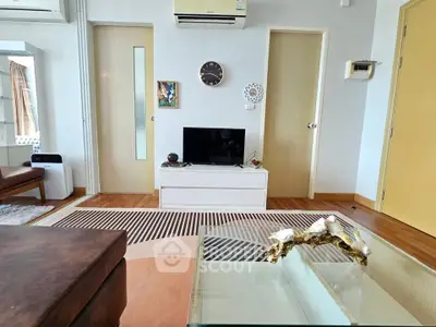 Stylish living room with modern decor and air conditioning, featuring a cozy seating area and sleek TV stand.