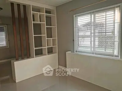 Spacious room with built-in shelving and large window, perfect for modern living.