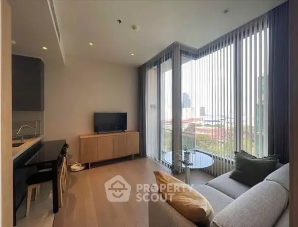 Modern living room with large windows and city view, featuring sleek furniture and open layout.