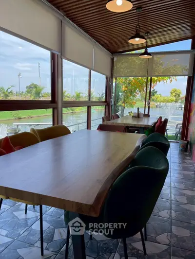Charming sunlit dining area with large windows and garden view, perfect for gatherings.