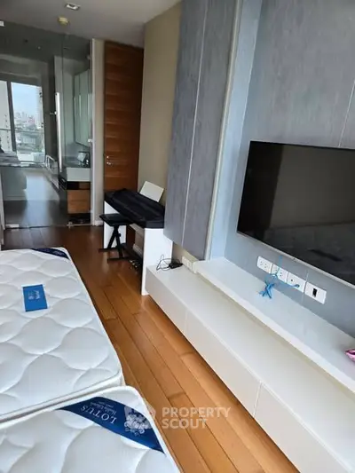 Modern bedroom with hardwood floors, wall-mounted TV, and large window view.