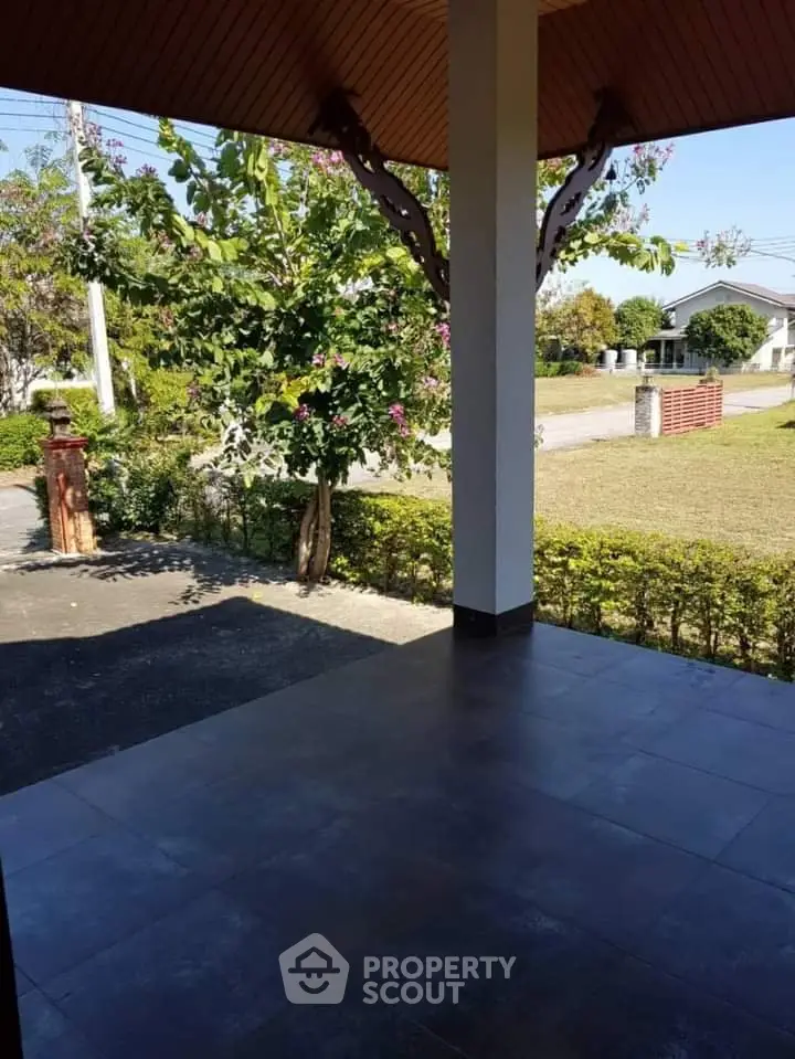 Charming outdoor patio with lush greenery and spacious tiled flooring, perfect for relaxation and outdoor activities.