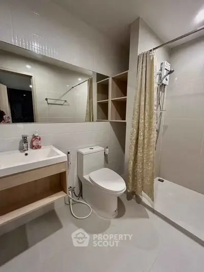 Modern bathroom with shower, toilet, and sink in sleek design.