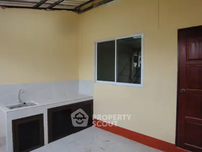 Simple kitchen with closed layout and window, featuring basic cabinetry and sink.