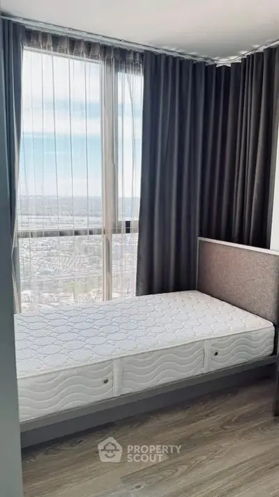 Modern bedroom with large window offering stunning city view, featuring sleek design and natural light.
