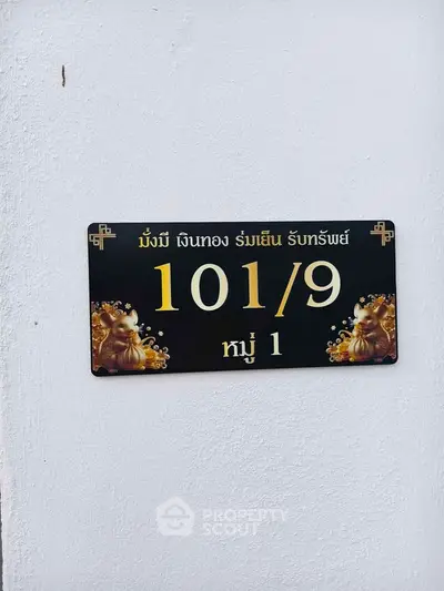 Elegant house number sign with gold accents on a white wall, showcasing Asian-inspired design.