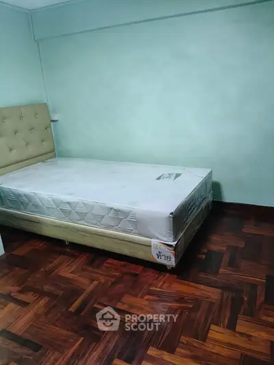 Cozy bedroom with parquet flooring and a comfortable bed, perfect for relaxation.